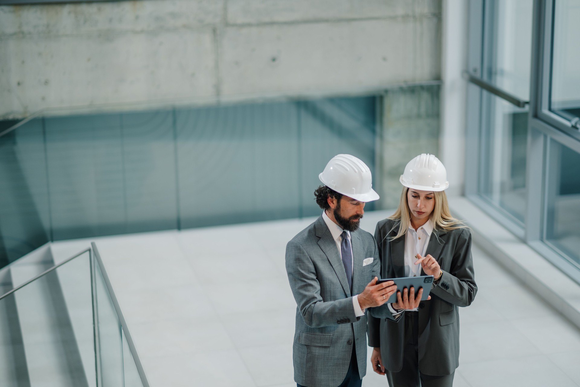 Architects using digital tablet discussing blueprint in modern building