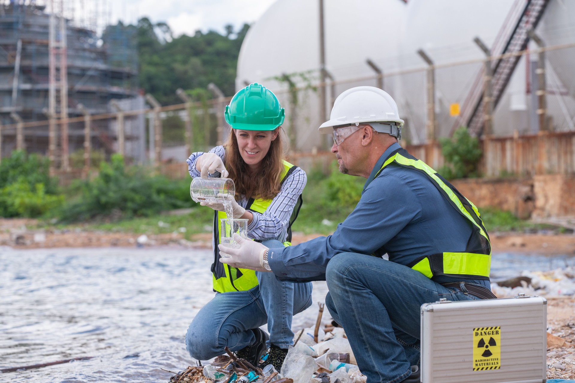 Environmental engineer or workers examining waste water along a  large industrial waste water or pollution monitoring and maintenance to ensure systems operate effective environmental regulations.